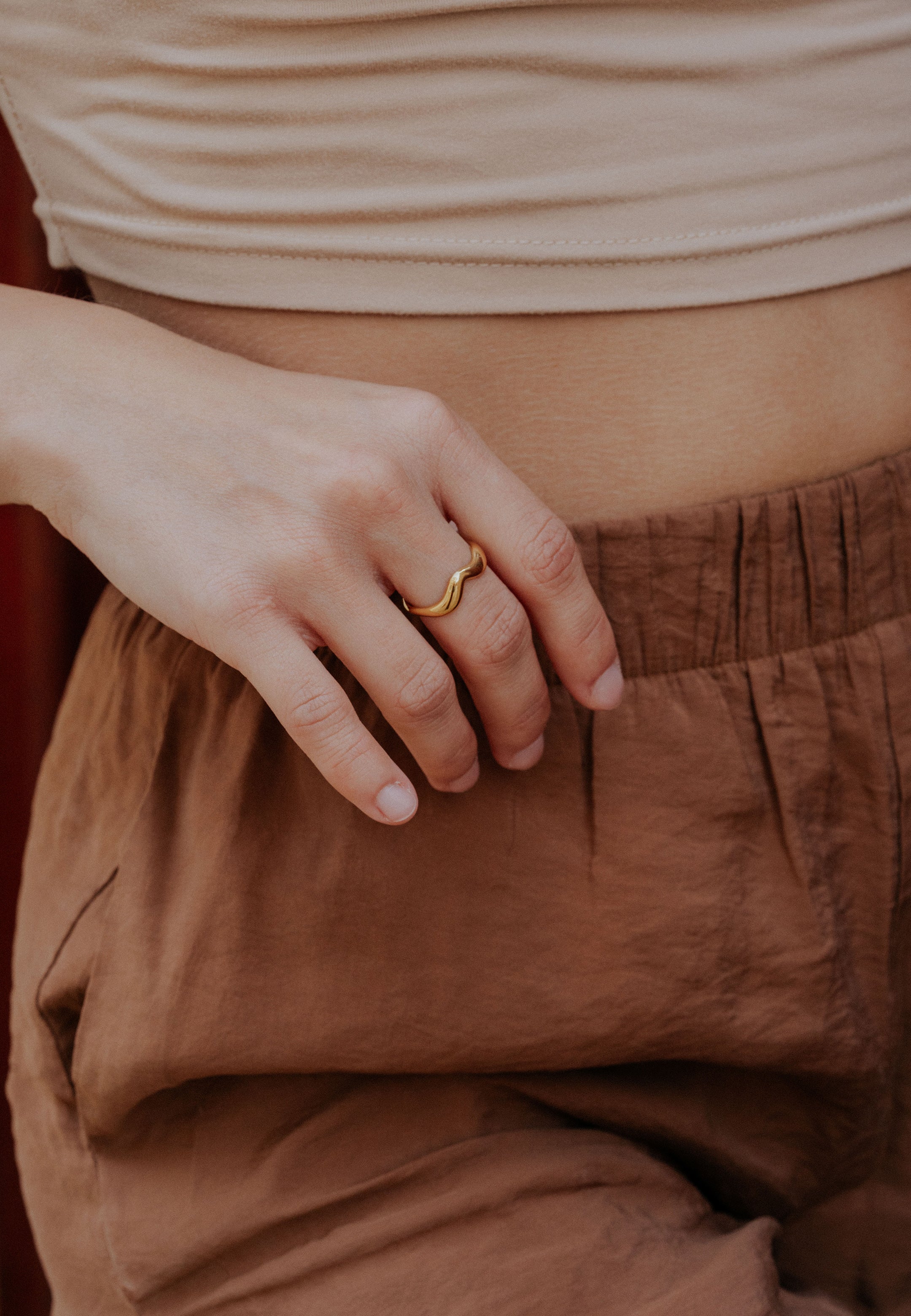 Close-up of a person wearing a gold ring on a blurred background