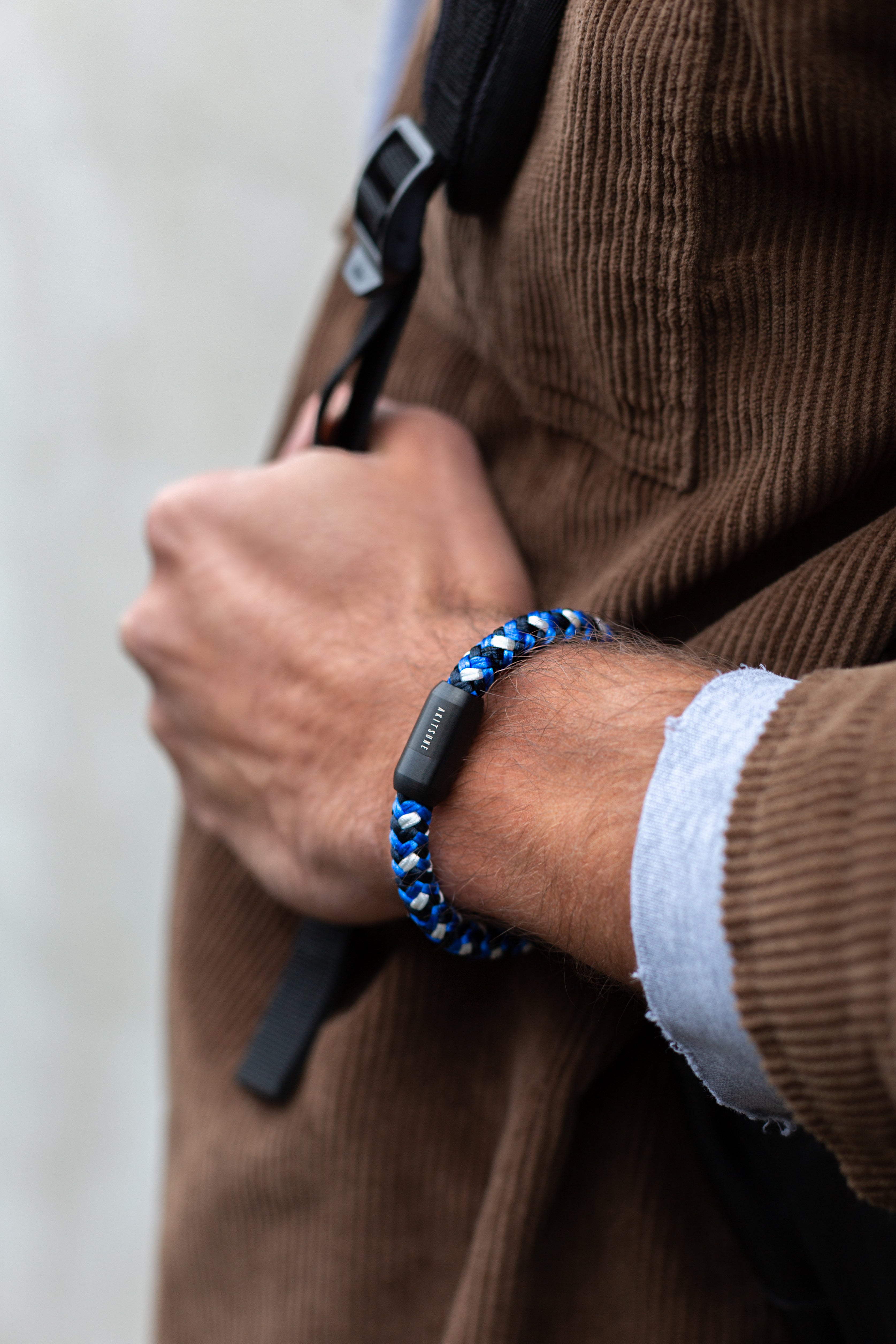 Person wearing a blue and black braided bracelet on a blurred background