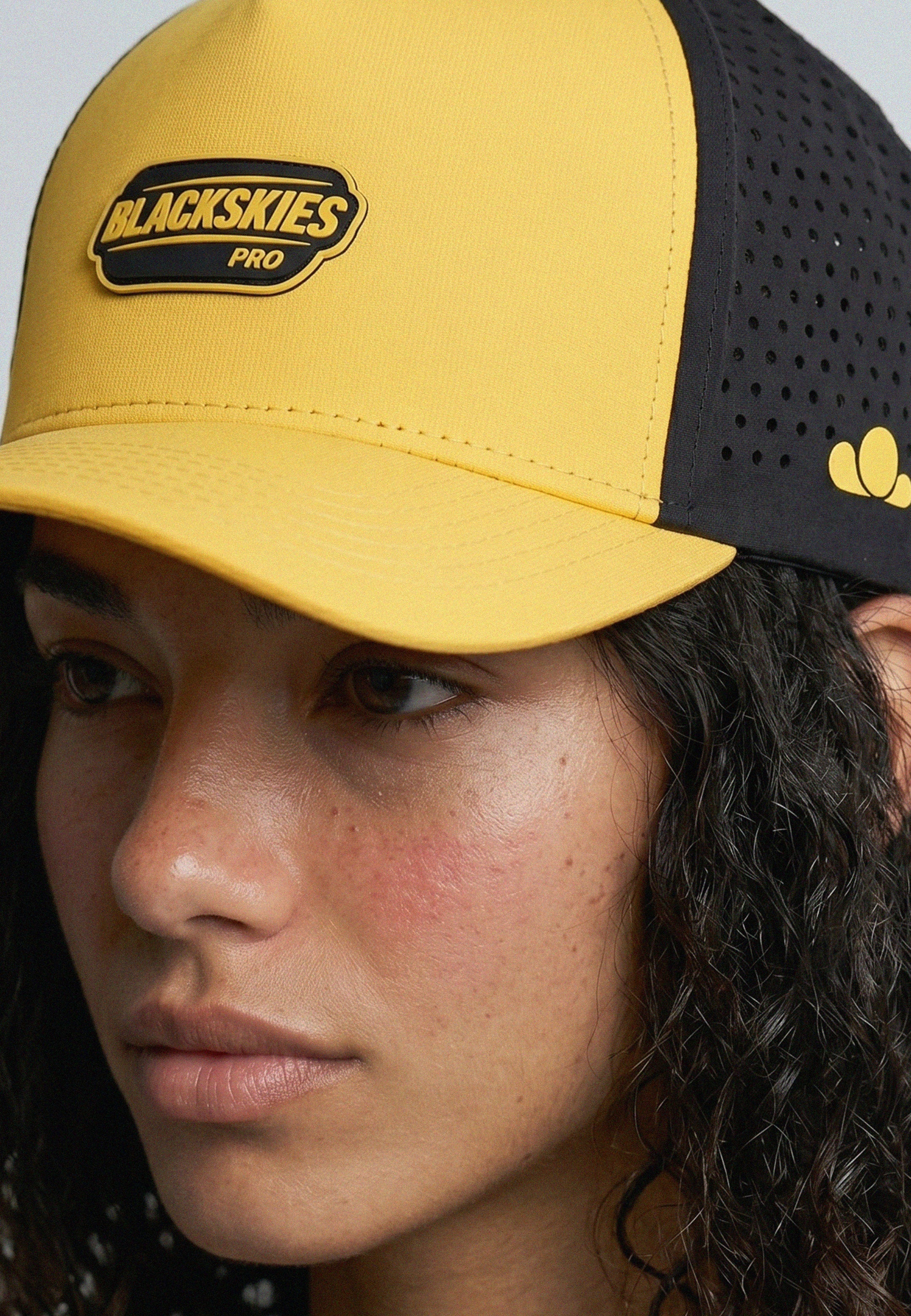 Person wearing a yellow and black cap with 'Blackskies Pro' logo