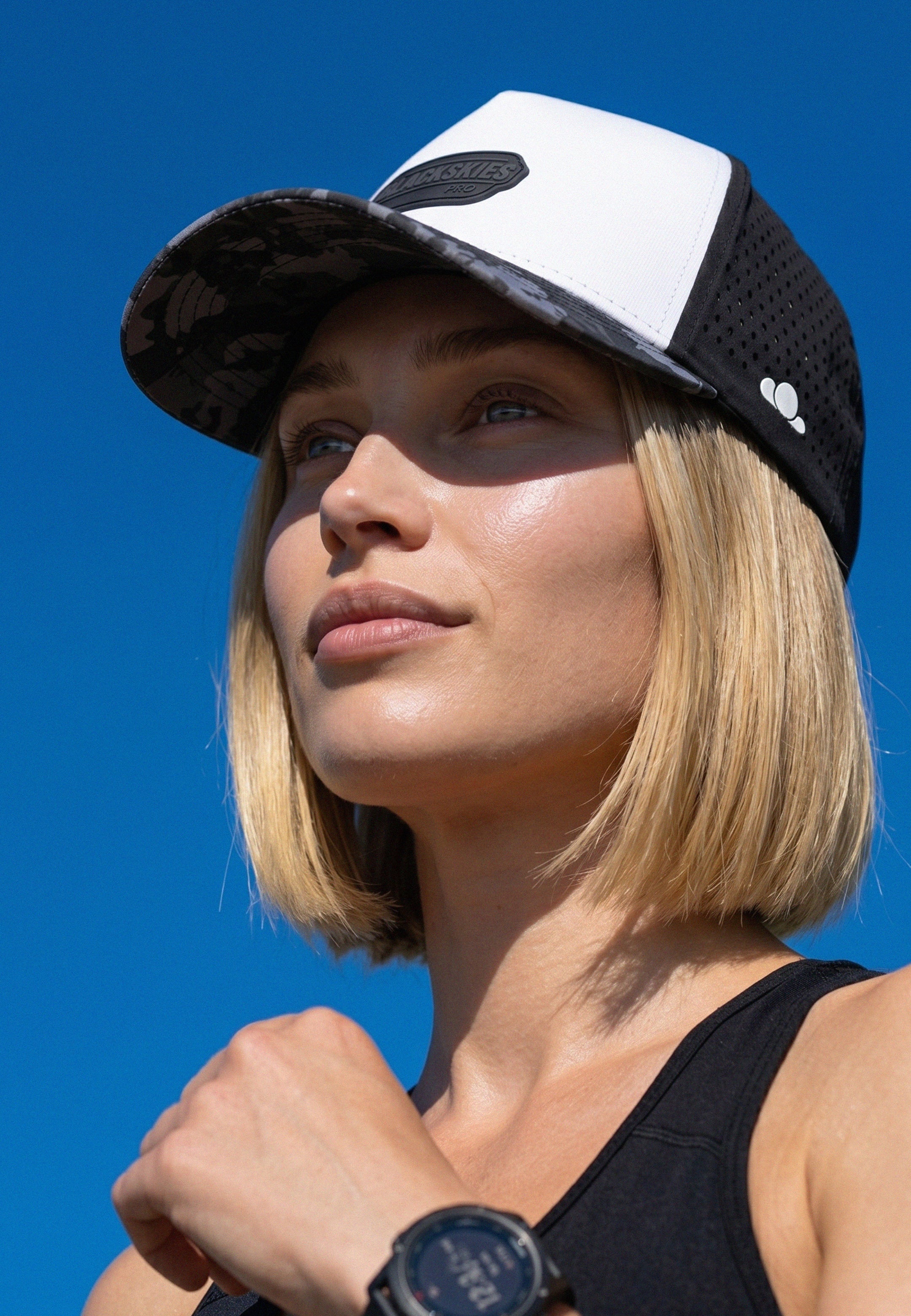 Woman wearing a black and white cap against a blue sky