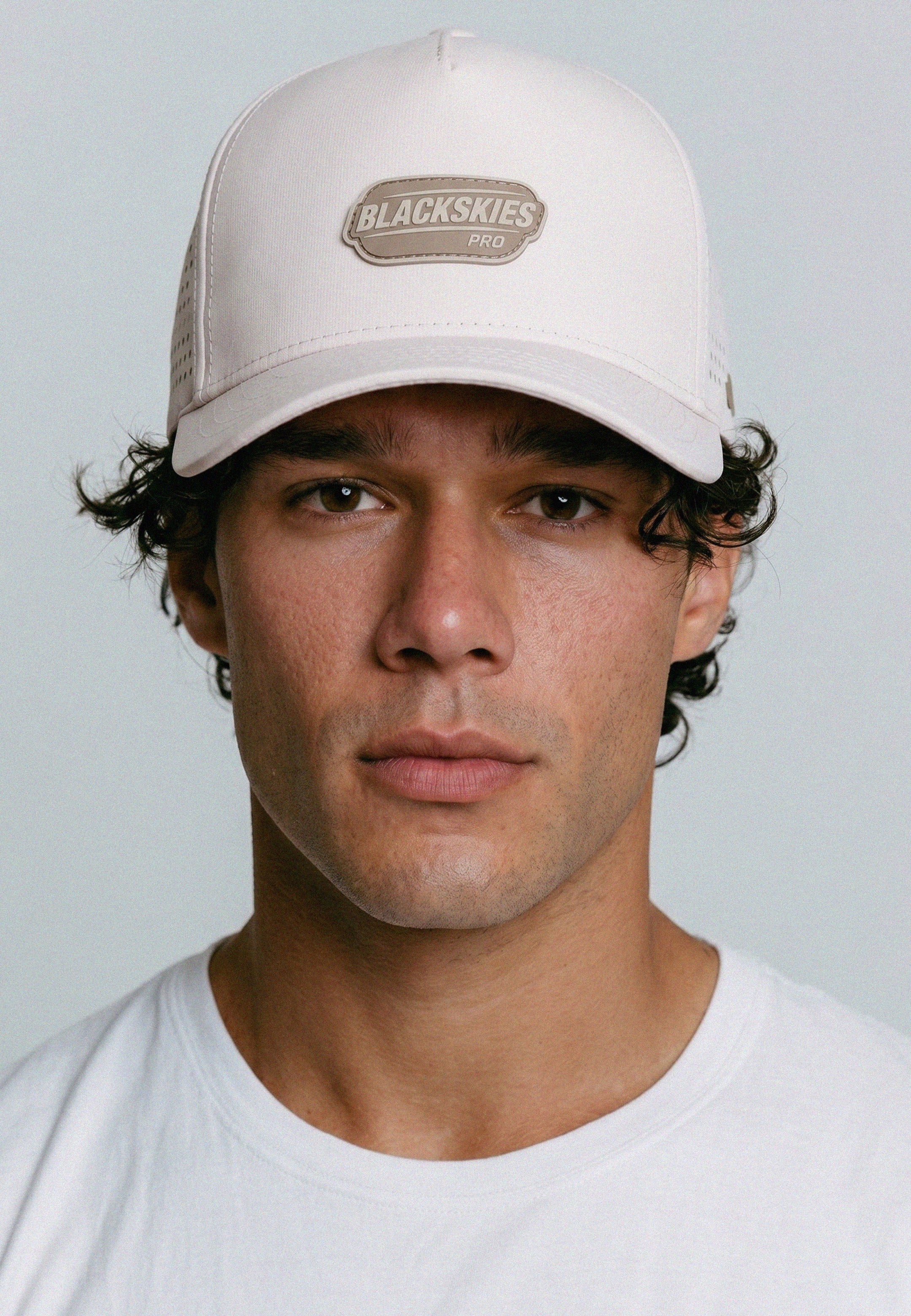 Man wearing a beige cap with 'Blackskies' logo on a light gray background