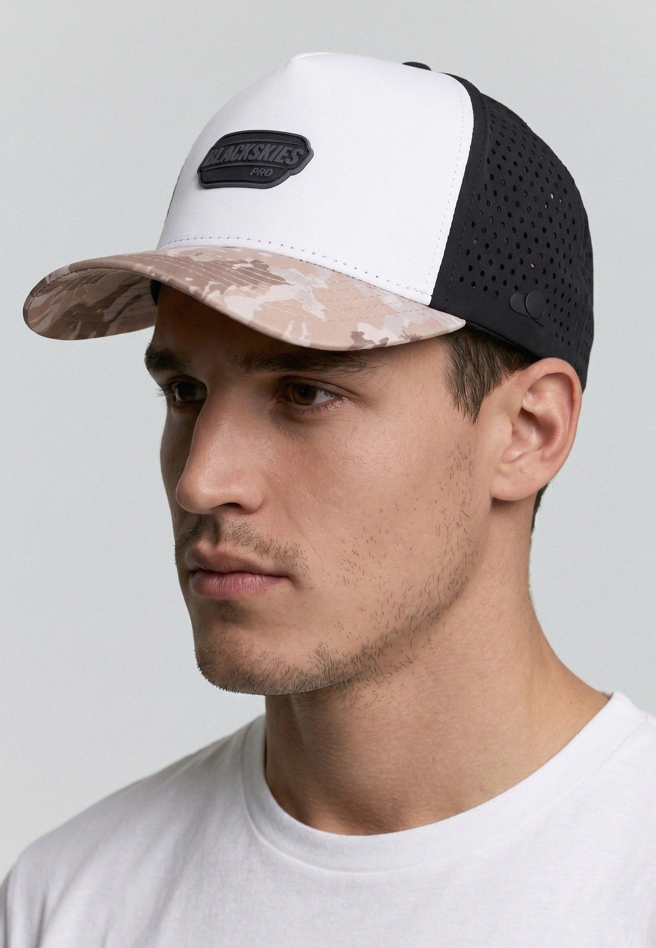 Man wearing a cap with a camouflage pattern on a plain background