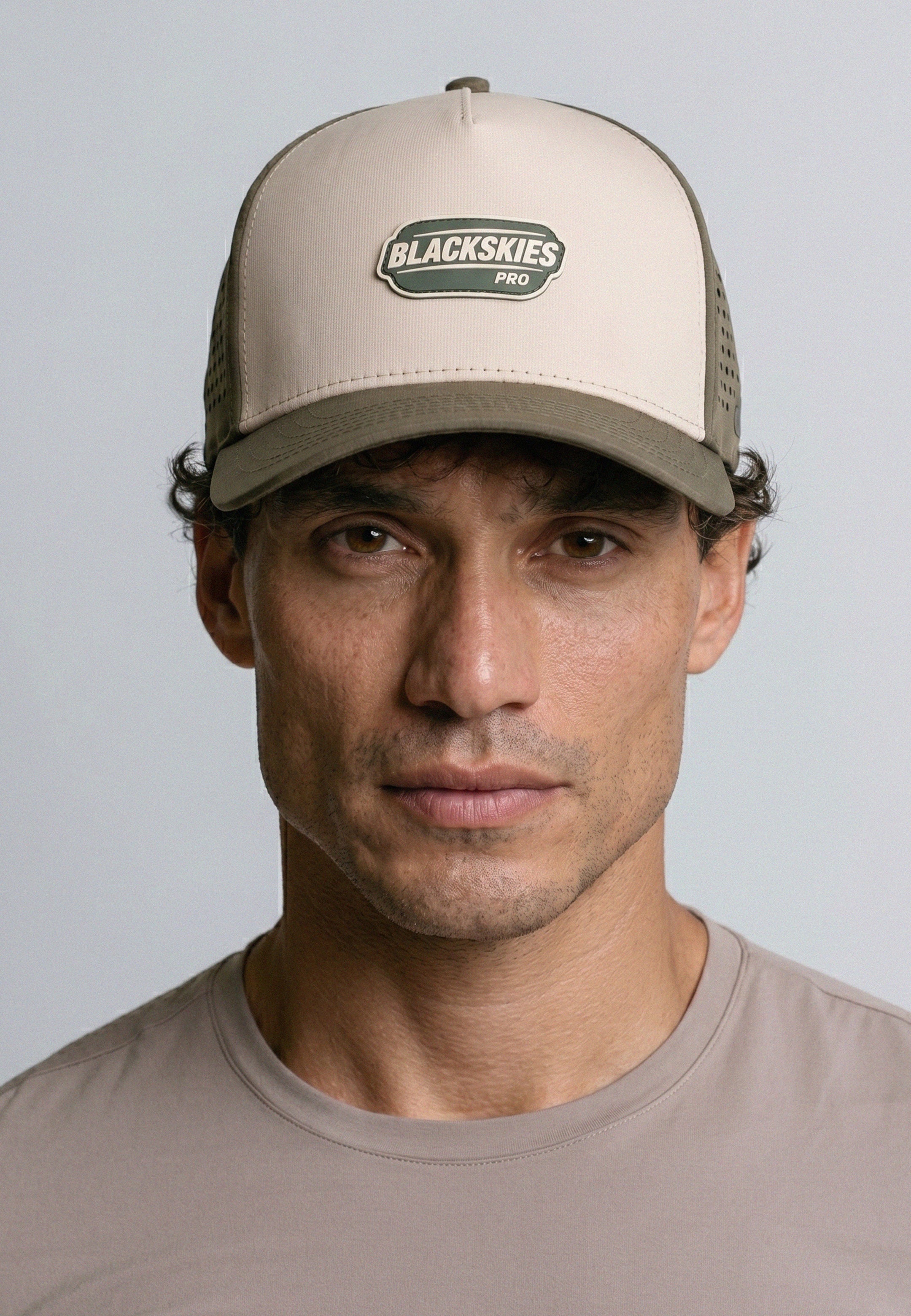 Man wearing a beige cap with 'Blackskies Pro' logo against a gray background