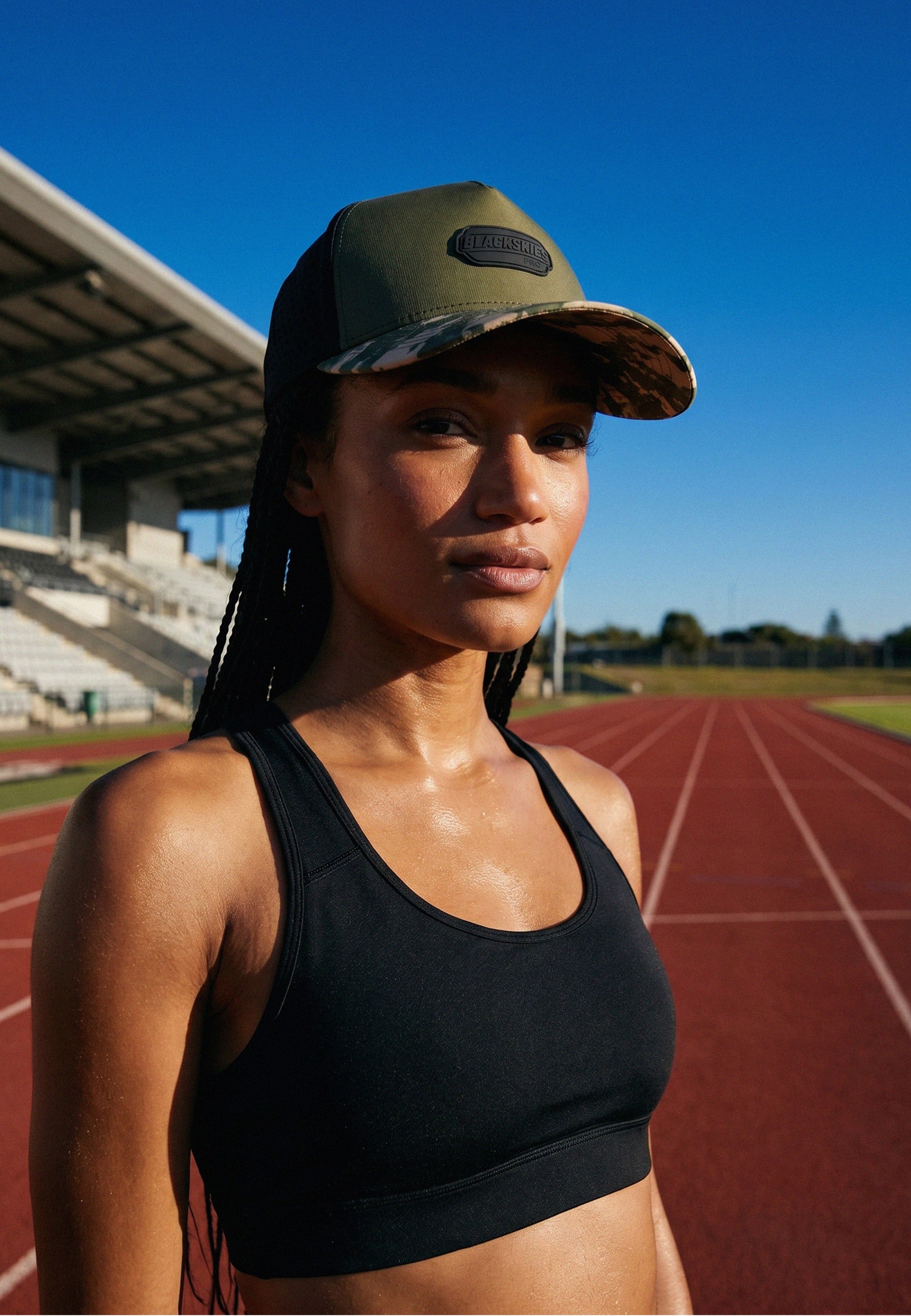 Woman wearing a cap and sports bra on a running track