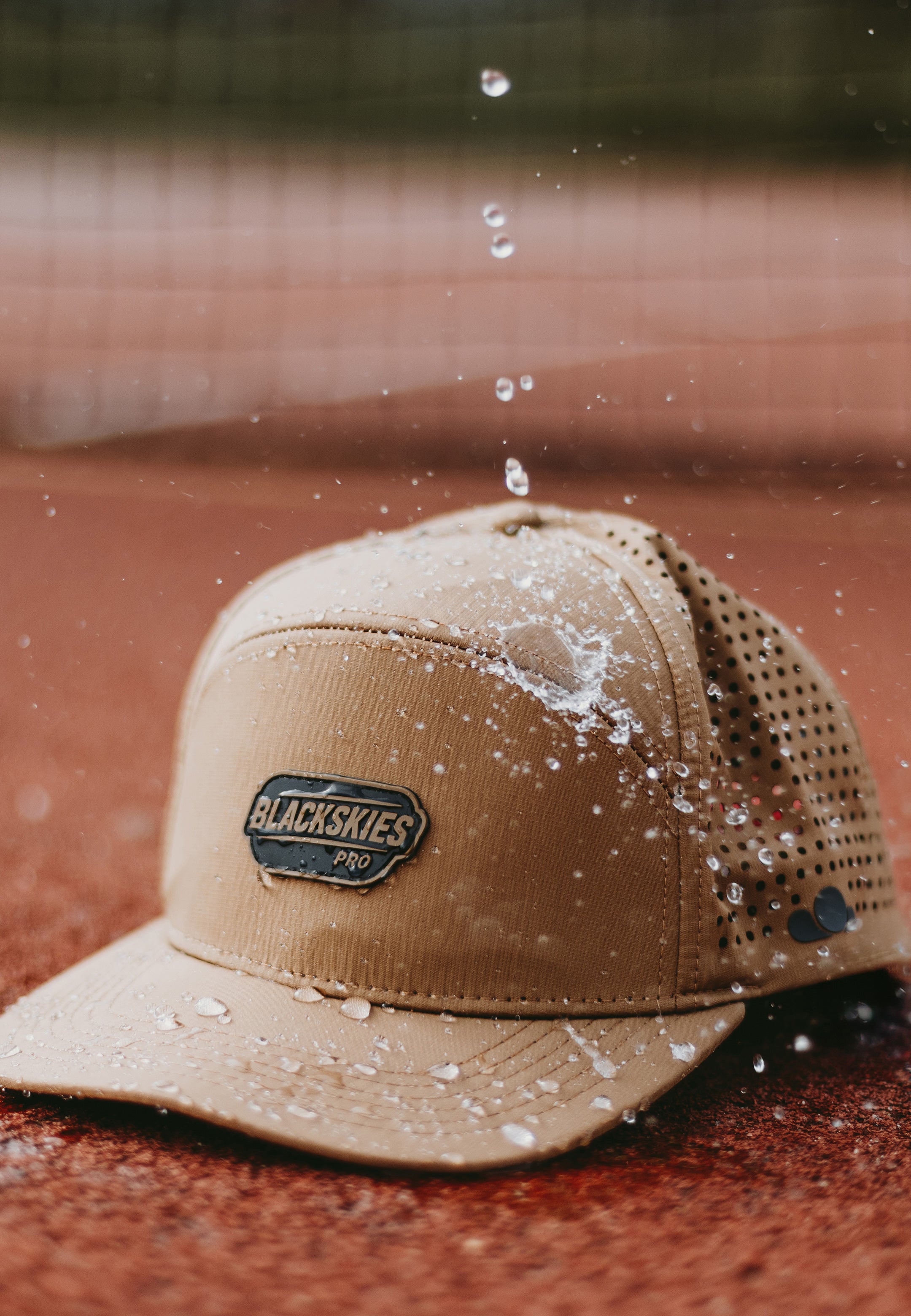 Water repellent sport performance cap in brown with blackskies gum logo on tennis court