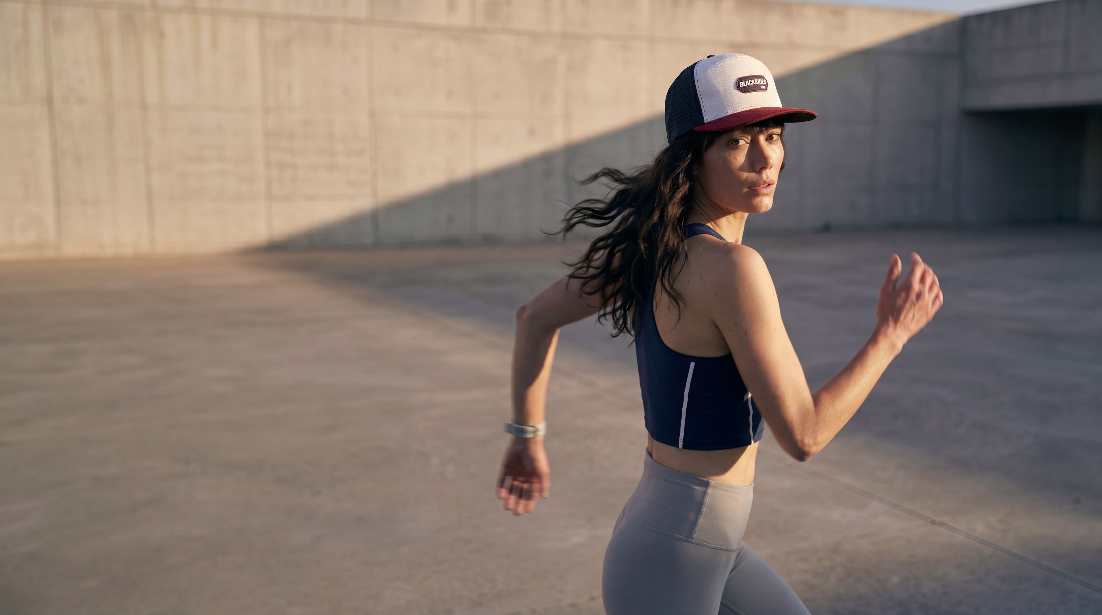 Woman running outdoors wearing a performance sport cap from blackskies and athletic wear.