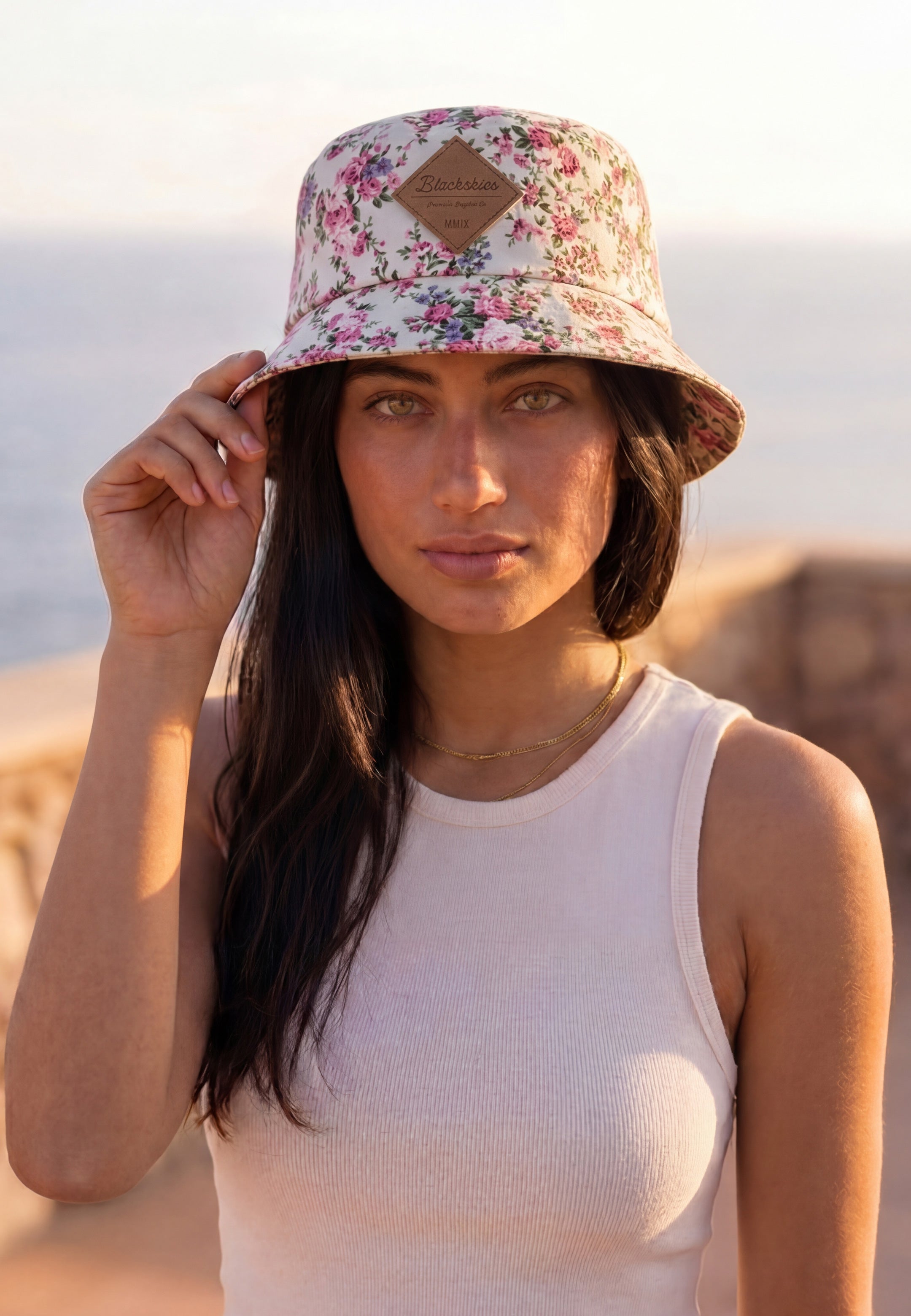 Woman wearing a floral bucket hat from blackskies in a holiday sun setting